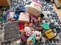 Overview of stuffed animals, toys, storage bins, knitted hats, and accessories arranged on floor