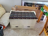 Storage bench closed, showing white paint, two drawers, and southwestern patterned cushion on top.