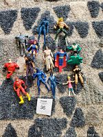 Top view of entire lot of 15 small action figures arranged on a rug, showing characters in various colors and positions, one missing a head.
