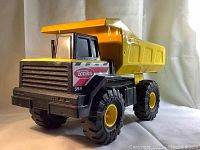 Three different angles of the Tonka Mighty Dump Truck showing front-left side, rear, and back views of tilt-back dump bed and wheels.