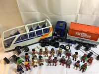 Cargo truck, bus, extra wheels, and 23 Play Mobile figures shown together on a plain background