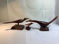 Photo of all three wooden bird sculptures showing two large birds on stands and one small bird sculpture in front