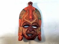 Front view of the colourful wooden mask showing detailed carving and painted indigenous patterns