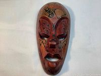 Frontal view of the carved wooden mask showing detailed painted First Nations style designs and facial features.