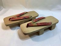 Pair of traditional Japanese geta wooden sandals shown from an angled top view, displaying the wood base and colorful fabric thong straps.