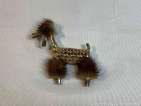 Front view of metal poodle brooch pin showing detailed woven metal body and brown faux fur accents on head, chest, and legs.
