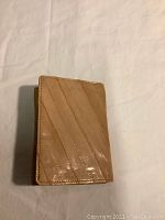 Closed view of light brown eel skin wallet showing diagonal linear pattern and glossy finish.