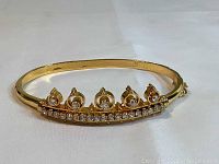 Front view showing gold-tone metal bracelet with tiara design and sparkling clear rhinestones along front band