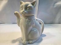 Front angled view of white cat-shaped porcelain teapot showing facial features, spout, and ears