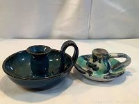 Two vintage ceramic candle holders with handles side by side, showing color and shape differences