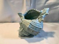 Side view of the large ceramic conch shell dish bowl showing textured shell design and blue-green glaze.