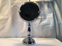 Front view of chrome double-sided rotatable makeup mirror on a weighted base.