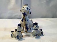 Front view of the three poodle figurines with visible chains