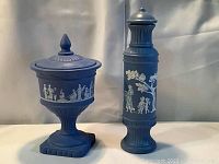 Full view of the blue covered urn and tall perfume bottle with classical white reliefs.