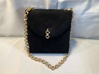 Front view of the vintage black suede purse with golden chain strap, showing the flap closure and chain draped in front.