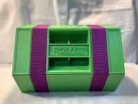 Front view of the green Rolykit toolbox with purple straps and molded handle embossed with brand name.