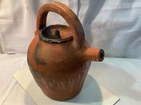 Front angle of the handmade pottery pot showing the body, spout, arched handle, and lid.