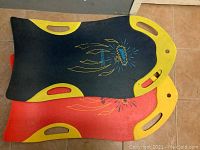 Two foam carpet sleds stacked, showing the top part of the dark blue sled with yellow accents and red sled underneath.