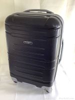 Front angle view of the black hard shell suitcase with visible Olympia brand plate, textured finish, and spinner wheels.