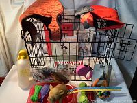 Lot overview with dog cage in background and assorted dog accessories arranged in front including coats, toys, water dispenser, bowls, leash, and books.
