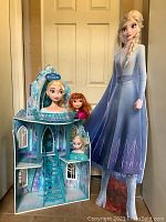 Photo showing the ice castle dollhouse, the life-size Elsa standup cutout, and the three character busts arranged together.