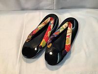 Front angled view of the Japanese geta style flip-flops showing black cushioned sole and colorful floral fabric straps.