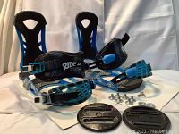 Photo showing side angle of bindings with mounting discs and mounting hardware bolts and washers in front, detailing binding straps and metal baseplate.