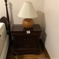 Single table next to bed with lamp on top