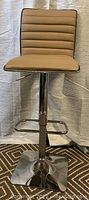 Front view of brown leather bar stool mounted on chrome pedestal with square base and footrest