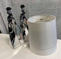 Two twisted chrome finish table lamp bases next to white fabric shades
