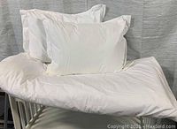 Photo of the queen size white duvet cover displayed on a white cot along with two matching white pillows and pillow shams.