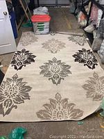 Full view of beige area rug with large brown, tan, and grey damask motifs on floor