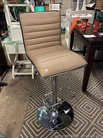Front view of a brown leather upholstered bar stool showing seat, back and chrome pedestal base