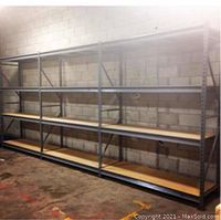 Three connected metal shelving sections installed against a block wall, each with four wood shelves