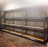 Three-section metal racking system assembled side by side against a concrete block wall, showing wood shelves and metal frame