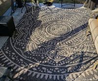 Angled photo of the full patio rug showing the circular geometric pattern and outdoor patio setting.