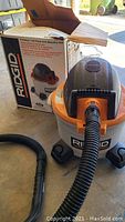 Front and side view of Ridgid wet/dry vacuum with box in background showing model information.