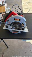 Full view of red and silver Craftsman 7.25-inch circular saw on black table showing blade and handle with power cord coiled