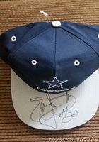 Photo of the Dallas Cowboys cap showing the star logo and autographs on the brim.