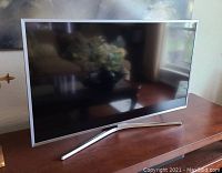 Front-angled view of TV powered off on wooden surface