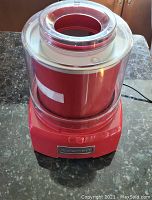 Front view of Cuisinart red automatic ice cream maker on granite counter showing base, controls, and transparent bowl with lid.