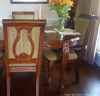 Set of two Harmony Georgian arm chairs with harp back design, horse hoof front legs, upholstered golden brown seats, and burnished cherry wood frames around a dining table.