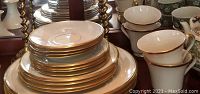 Photo showing stacked Lenox Eternal plates and footed cups with gold bands, ivory porcelain set