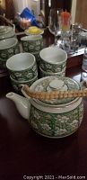 Five-piece green floral Japanese tea set with teapot and cups shown on a dark table.