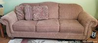 Frontal view of sofa showing three seat cushions, attached back cushions, rolled arms and two decorative throw pillows
