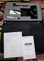 Top view of the Saunders Cervical HomeTrac device and accessories arranged inside a foam-lined black carrying case including user guides.