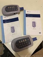 Photo showing two Nellcor SpO2 tester devices and two spiral-bound user manuals on a table surface.