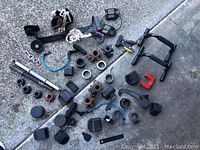 Various fitness equipment parts laid out on the ground including grips, collars, handles, a metal chain, and rubber foot pads.