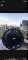 Side view of black cast iron weight plate with large raised white lettering 'WASHINGTONIAN' and '25 LBS'.