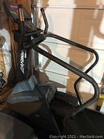 Side view of the stepper showing dual handrails, textured foot pedals and base housing